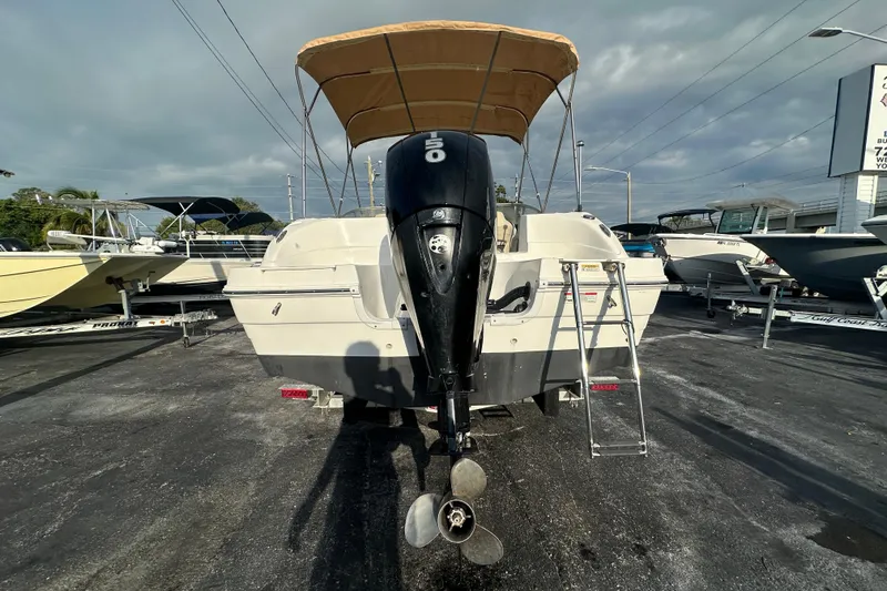 Slide: The Image of 2020 Hurricane SunDeck 217 OB boat with outboard motor and canopy, parked on asphalt. - 4
