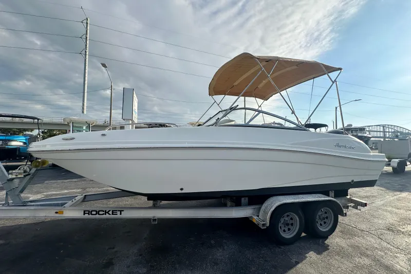 Slide: The Image of 2020 Hurricane SunDeck 217 OB boat on trailer with canopy, parked outdoors. - 7