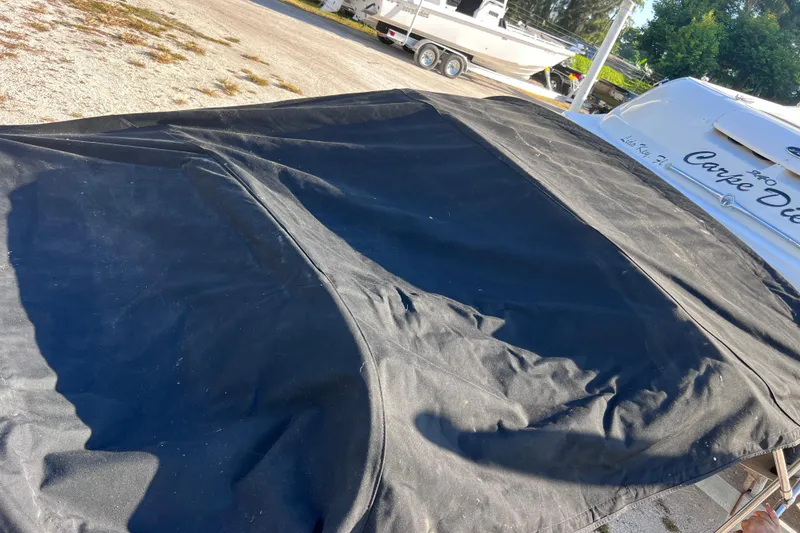 Slide: The Image of 2006 Sea Ray 240 Sundeck with black cover, parked outdoors. - 34