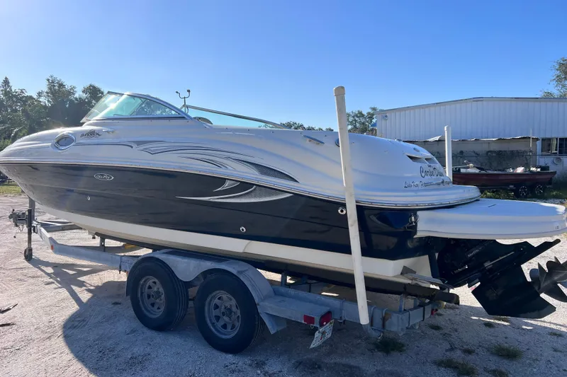 Slide: The Image of 2006 Sea Ray 240 Sundeck boat on trailer, parked outdoors under clear blue sky. - 6