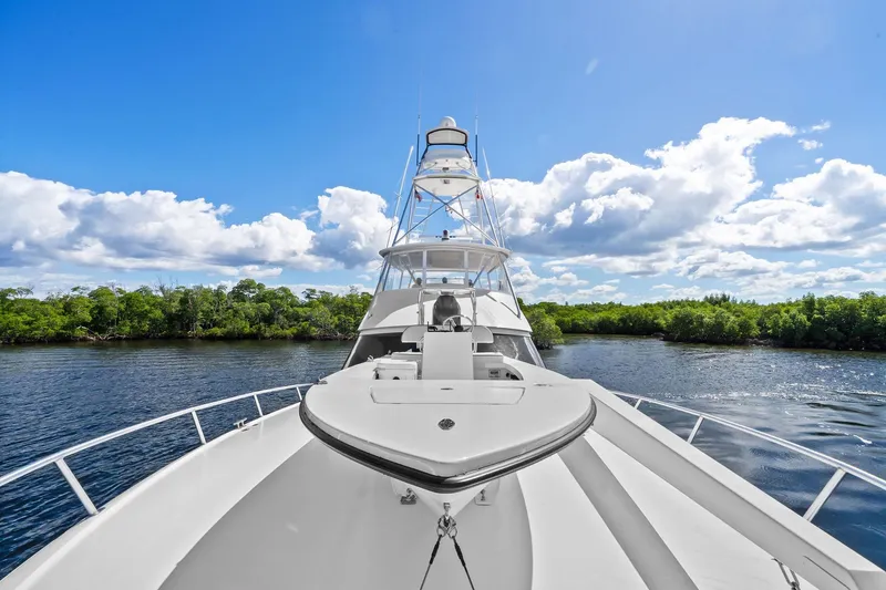 Slide: The Image of 2015 Viking 66' Convertible yacht cruising on a scenic river under a bright blue sky. - 14