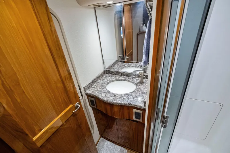 Slide: The Image of Luxurious bathroom in 2015 Viking 66' Convertible yacht with granite countertop and wooden cabinetry. - 50