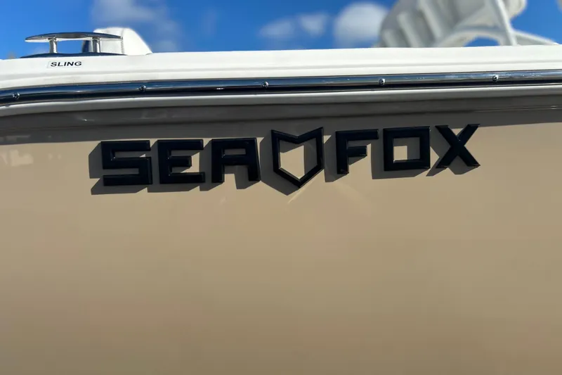 Slide: The Image of 2026 Sea Fox 228 Commander boat logo on beige hull under blue sky. - 1