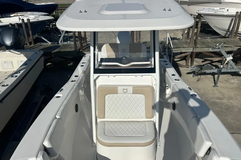 Slide: The Image of 2026 Sea Fox 228 Commander boat with white and beige seating, docked at a marina. - 11