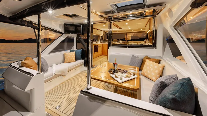 Slide: The Image of Luxurious interior of 2024 Riviera 585 SUV yacht at sunset, featuring elegant seating and dining area. - 8