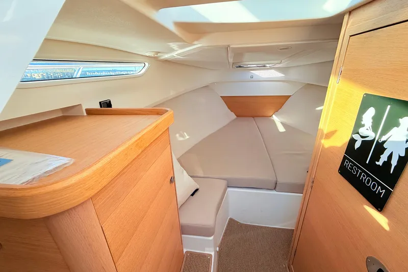 Slide: The Image of Cozy interior of 2023 Nimbus Weekender 9 boat with restroom sign and comfortable seating. - 10