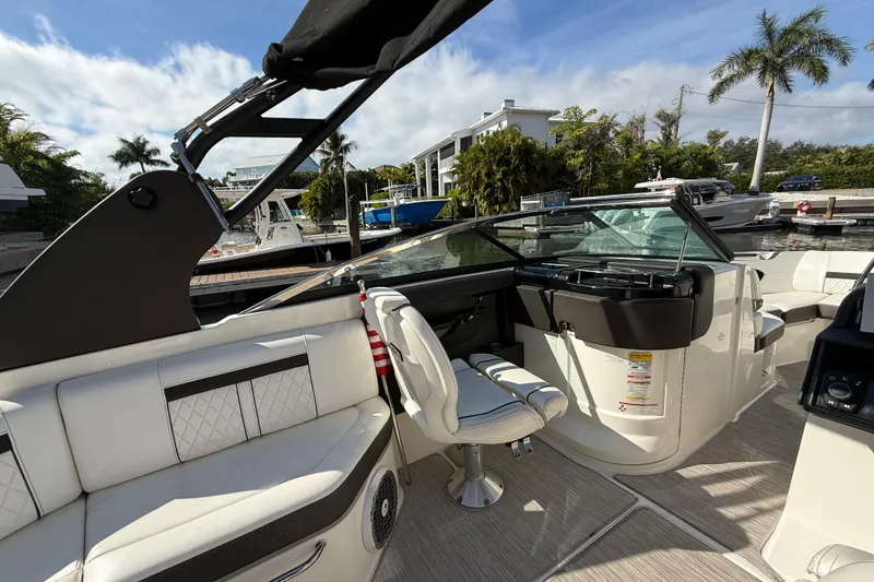 Slide: The Image of 2018 Sea Ray SLX 250 boat interior with white seating, steering console, and waterfront view. - 19