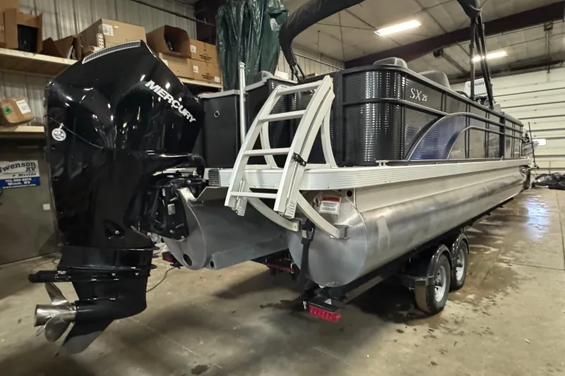 Slide: The Image of 2020 Bennington SXP 25 SSBXP pontoon boat with Mercury outboard in a garage setting. - 5
