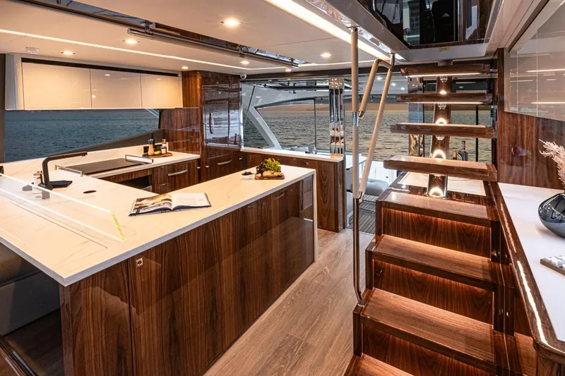 Slide: The Image of Luxurious interior of 2026 Riviera 64 Sports Motor Yacht Series II with modern kitchen and staircase. - 9