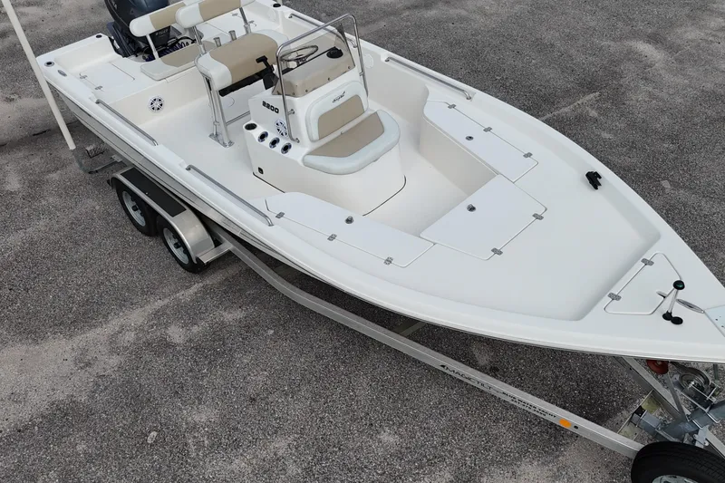 Slide: The Image of 2023 Bulls Bay 2200 boat on trailer, white deck, dual seats, parked on gravel. - 13