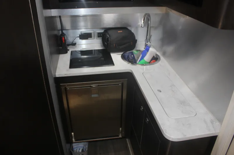 Slide: The Image of Compact kitchen area in a 2018 Scout 380 LXF boat, featuring a sink and stovetop. - 27