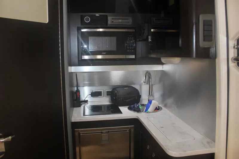 Slide: The Image of Compact kitchen area in a 2018 Scout 380 LXF boat with microwave and sink. - 34