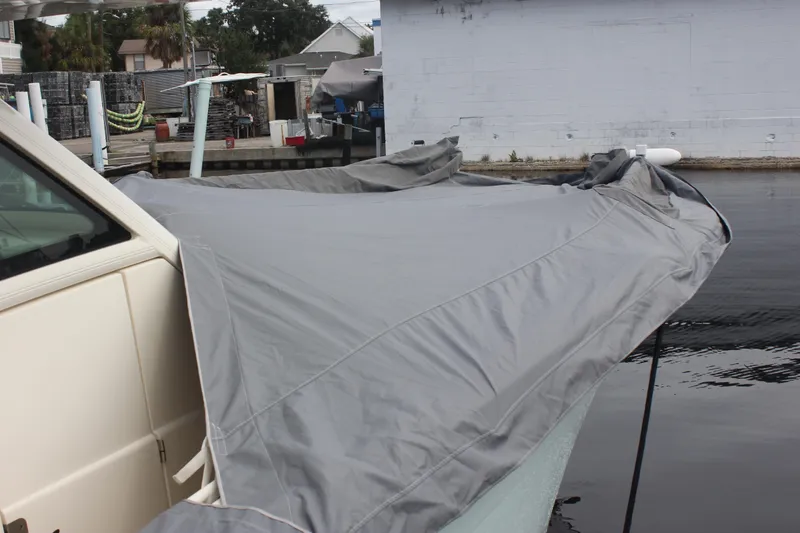Slide: The Image of 2018 Scout 380 LXF boat covered with a gray tarp at a dock. - 80