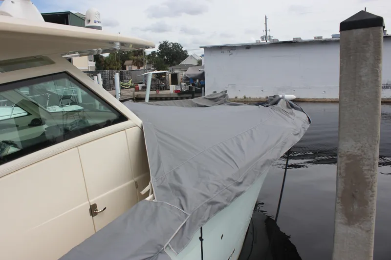 Slide: The Image of 2018 Scout 380 LXF boat covered at dockside, showcasing sleek design and protective cover. - 81