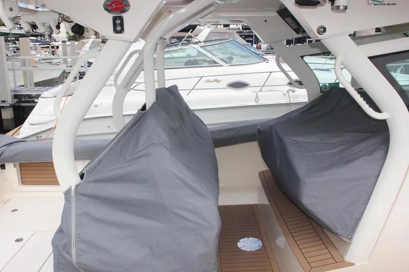 Slide: The Image of 2018 Scout 380 LXF boat interior with covered seating at a marina. - 83