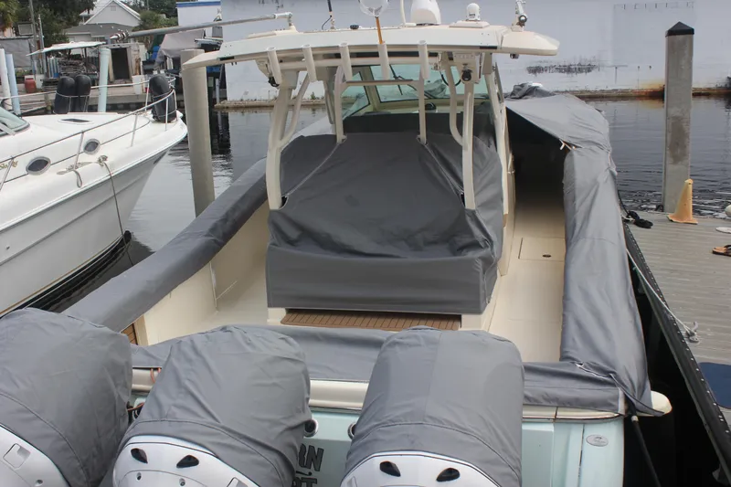 Slide: The Image of 2018 Scout 380 LXF boat docked, covered with protective gray tarps. - 86