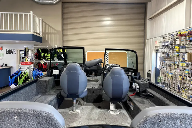 Slide: The Image of 2026 Alumacraft Voyageur 175 Sport boat interior in showroom with life jackets and accessories. - 4
