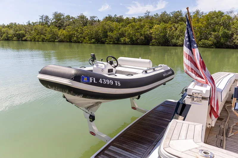 Slide: The Image of 2009 Sabre 52 Express yacht with tender lift and American flag on calm water. - 13