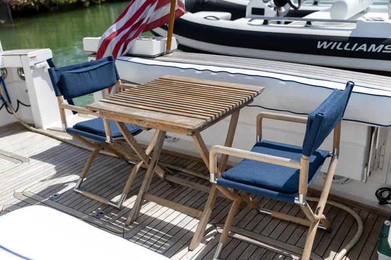 Slide: The Image of 2009 Sabre 52 Express yacht deck with wooden table and blue chairs. - 15