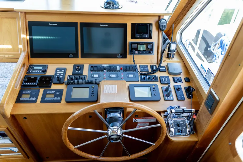 Slide: The Image of 2009 Sabre 52 Express helm with wooden steering wheel and advanced navigation controls. - 2