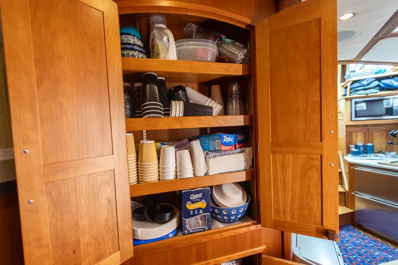 Slide: The Image of Wooden cabinet stocked with disposable cups and plates inside a 2009 Sabre 52 Express yacht. - 31