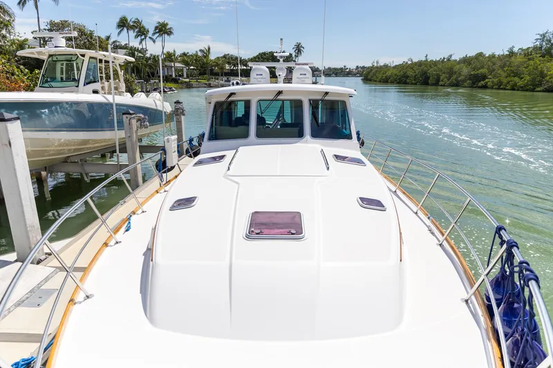 Slide: The Image of 2009 Sabre 52 Express yacht docked on a sunny day, surrounded by lush greenery. - 8