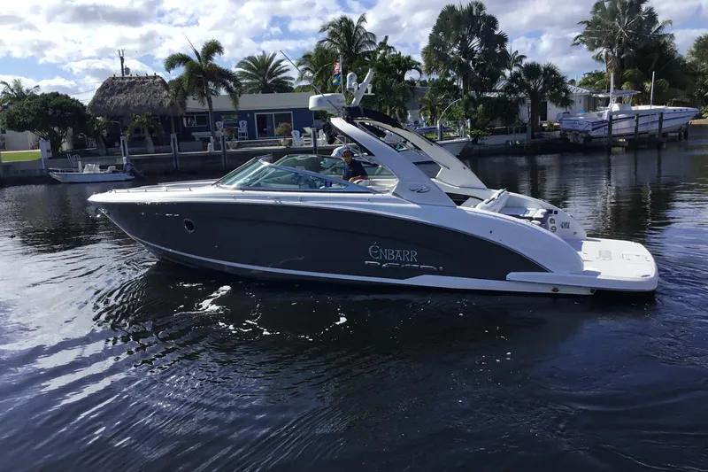 The Image of 2017 Regal 3200 Bowrider boat cruising on a calm waterway with palm trees in the background. - 0
