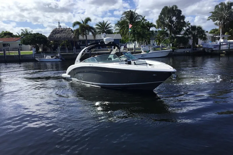 Slide: The Image of 2017 Regal 3200 Bowrider boat cruising on a sunny day near waterfront homes. - 10