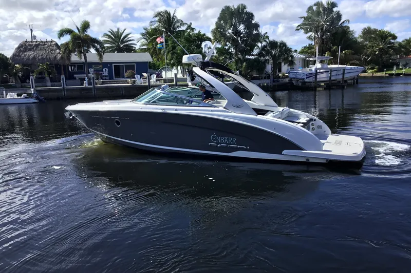 Slide: The Image of 2017 Regal 3200 Bowrider boat cruising on a calm waterway with palm trees in the background. - 2