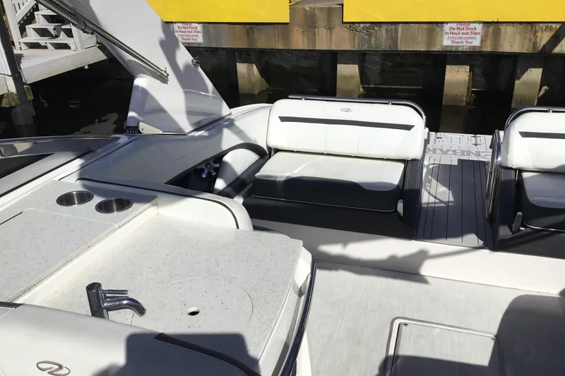 Slide: The Image of 2017 Regal 3200 Bowrider interior with seating and kitchenette, docked near a yellow wall. - 38