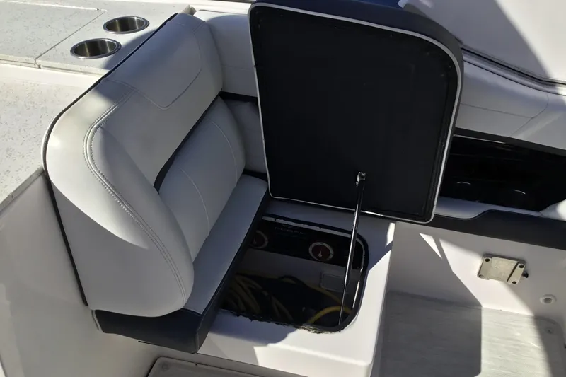 Slide: The Image of 2017 Regal 3200 Bowrider seat storage compartment with open lid and cup holders. - 42