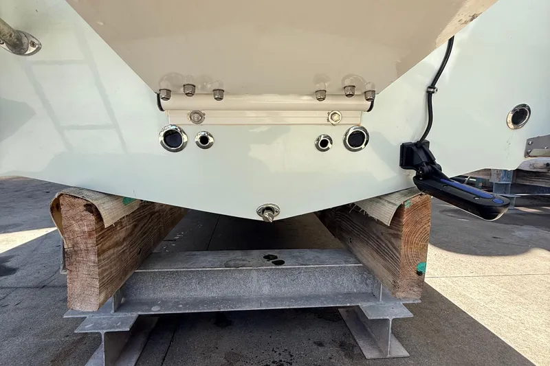 Slide: The Image of 2022 Dorado 25 Flat Deck boat hull on wooden supports, showcasing transom fittings. - 15