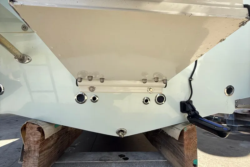 Slide: The Image of 2022 Dorado 25 Flat Deck boat transom with fittings and wiring, resting on wooden supports. - 16