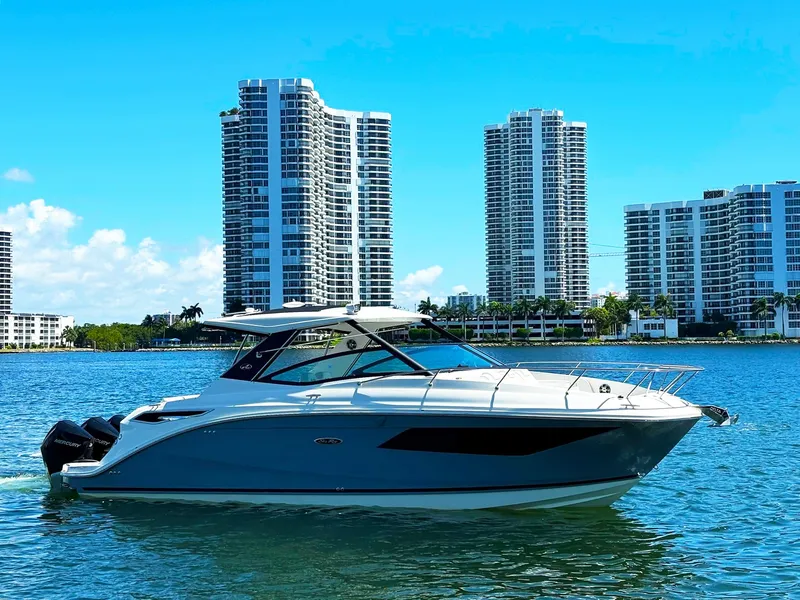 The Image of 2019 Sea Ray Sundancer 320 Outboard cruising near modern city skyline. - 0