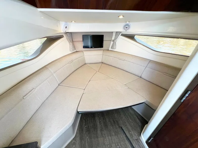 Slide: The Image of 2019 Sea Ray Sundancer 320 Outboard cabin interior with beige seating and small TV. - 17