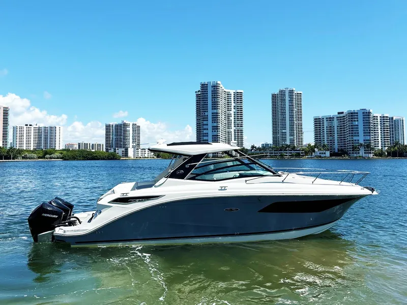 Slide: The Image of 2019 Sea Ray Sundancer 320 Outboard on water with city skyline in background. - 2