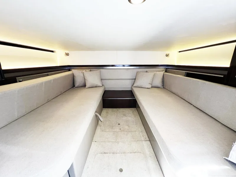 Slide: The Image of 2019 Sea Ray Sundancer 320 Outboard cabin interior with twin beige sofas and ambient lighting. - 20