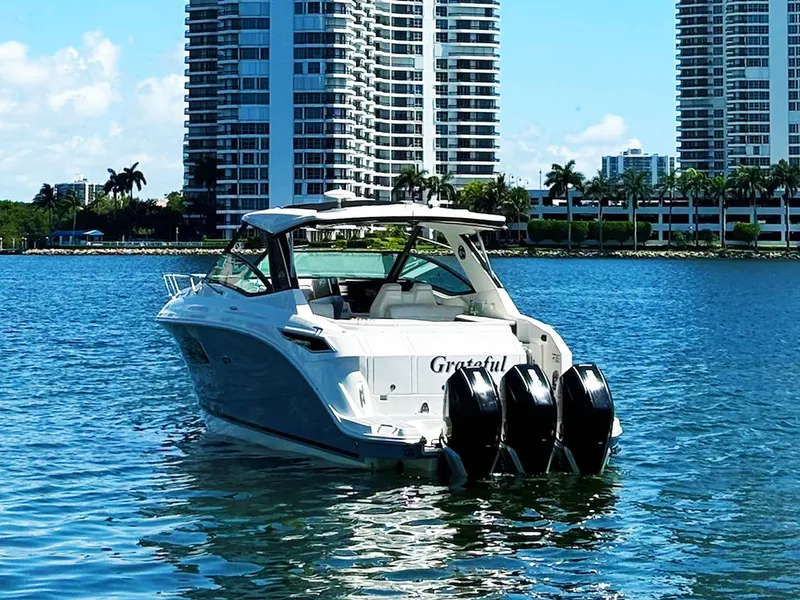 Slide: The Image of 2019 Sea Ray Sundancer 320 Outboard on water, city skyline in background. - 4