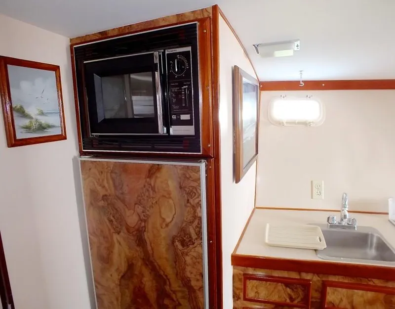 Slide: The Image of 1957 Rybovich Convertible yacht kitchen with microwave, sink, and wood paneling. - 10