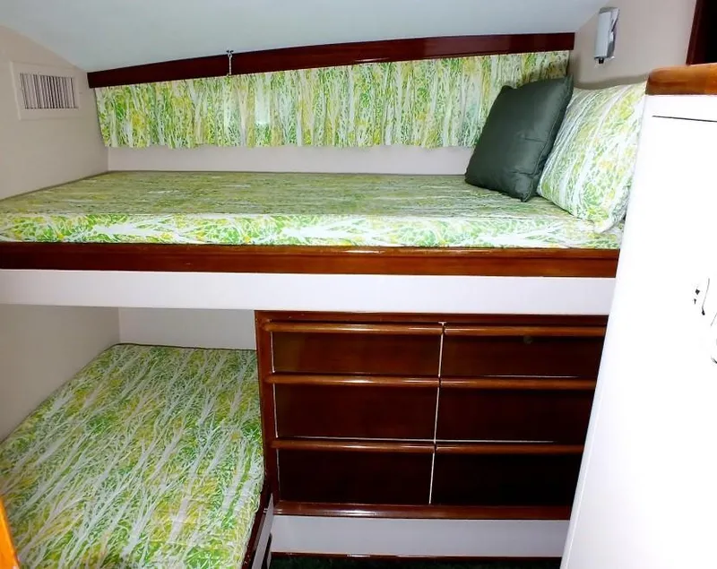 Slide: The Image of 1957 Rybovich Convertible interior with green-patterned bunk beds and wooden storage. - 13