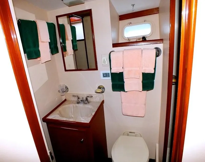 Slide: The Image of 1957 Rybovich Convertible yacht bathroom with sink, mirror, and neatly arranged towels. - 15