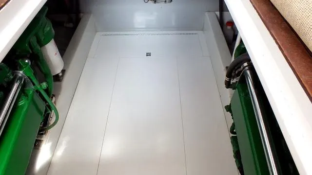 Slide: The Image of Engine room of a 1957 Rybovich Convertible boat, featuring green machinery and clean white surfaces. - 21