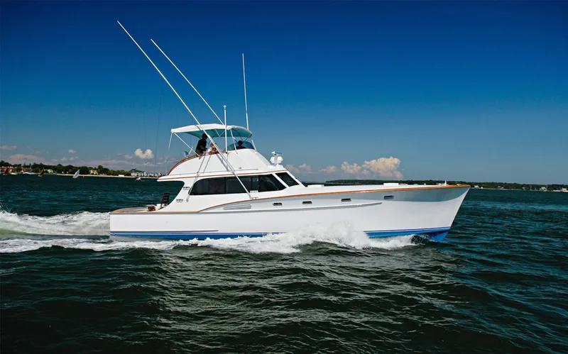 Slide: The Image of 1957 Rybovich Convertible yacht cruising on open water under a clear blue sky. - 26