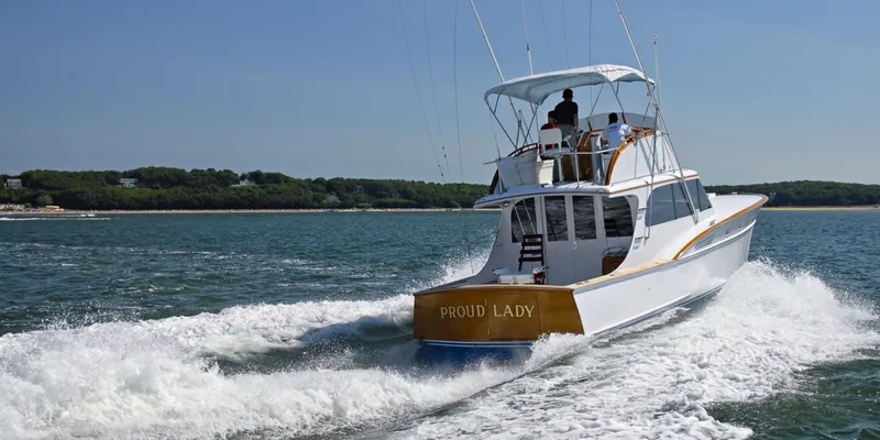 Slide: The Image of 1957 Rybovich Convertible boat cruising on open water, named "Proud Lady." - 28