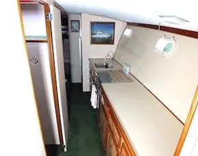 Slide: The Image of 1957 Rybovich Convertible yacht interior with kitchenette, wooden cabinets, and nautical decor. - 8