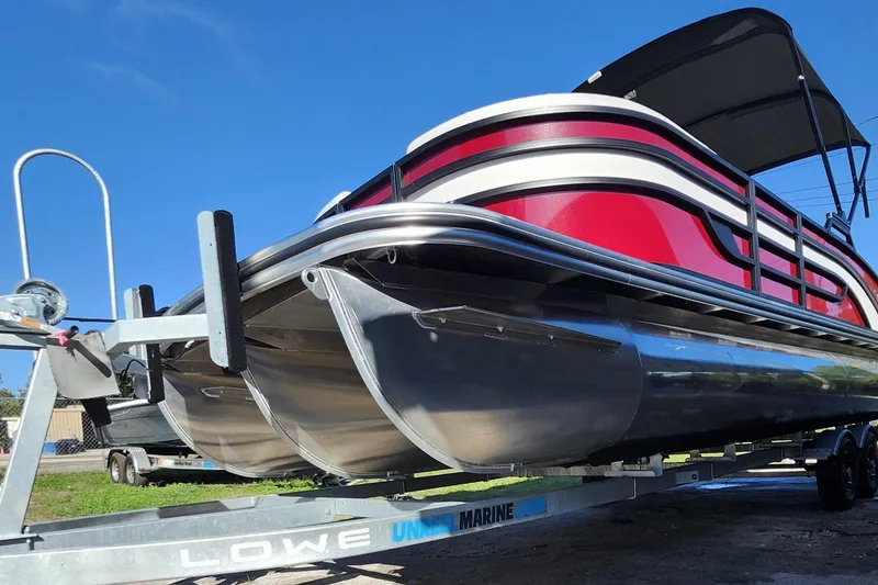 Slide: The Image of 2026 Lowe SS 230 DV pontoon boat on trailer, featuring sleek red and silver design. - 36