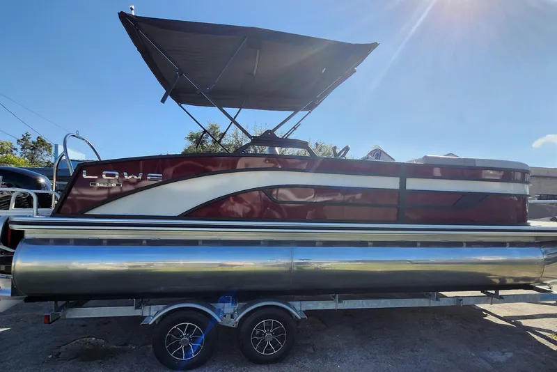 Slide: The Image of 2026 Lowe SS 230 DV pontoon boat with canopy on trailer, under sunny sky. - 38