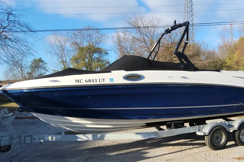The Image of 2022 Bayliner VR6 Bowrider OB on trailer, blue and white design, parked outdoors. - 1