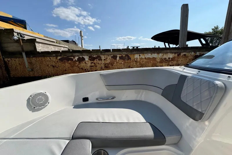 Slide: The Image of 2022 Bayliner VR6 Bowrider OB interior with cushioned seating and speaker, docked under blue sky. - 8