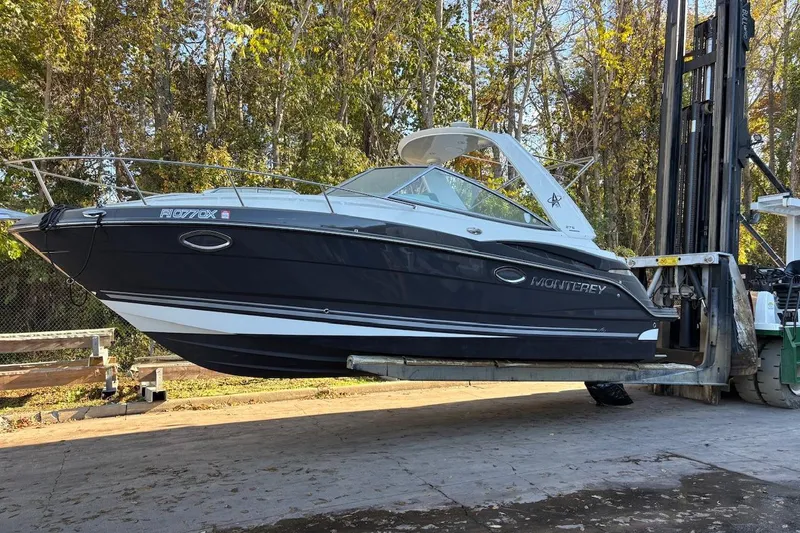 The Image of 2016 Monterey 275 Sport Yacht lifted by forklift, surrounded by trees. - 0